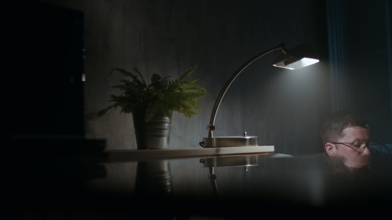 A sad man reads a book at night in his underwear