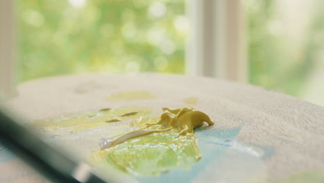 cerca de un lápiz mezclando pintura amarilla en una paleta de pintura de madera