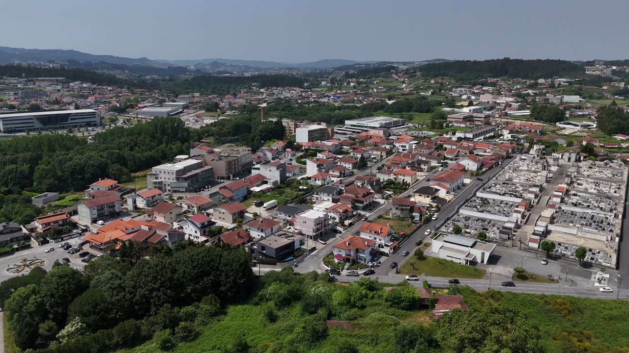 Aéreo - cidade de Paços de Ferreira com telhados vermelhos, campos, cemitério e colinas circundantes.