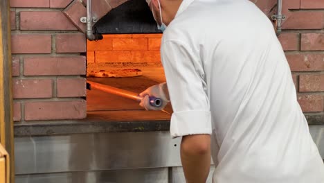 Un-Chef-Saca-Pizza-Del-Horno-Con-Fuego-Caliente