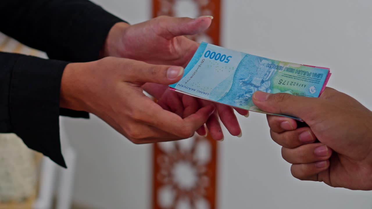 Close-up Tangan menerima zakat Fitrah dengan uang tunai di masjid