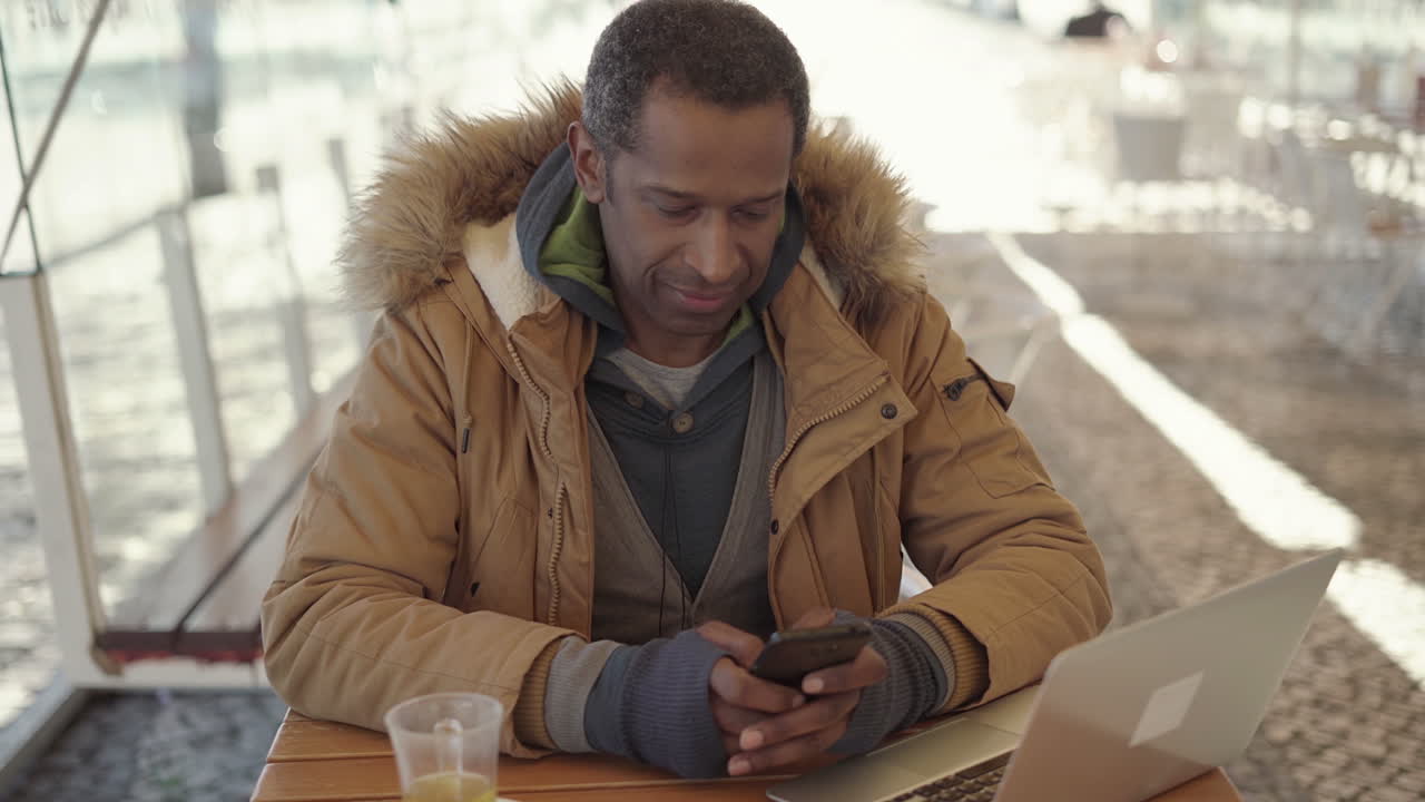 Man texting via smartphone in outdoor cafe