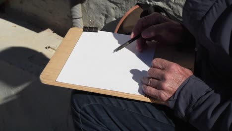 closeup of an artist's hand drawing a landscape on the street