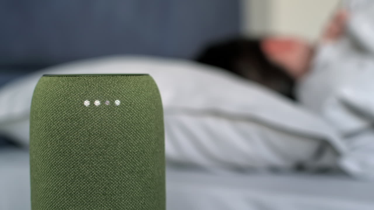 A sleeping woman turning off alarm clock on a portable wireless speaker with 4 luminous diodes