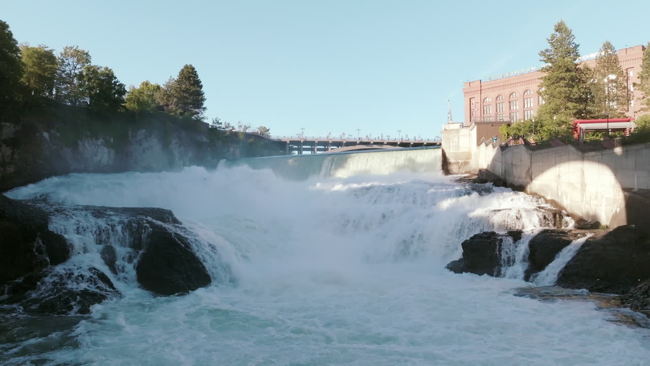 Water pounds down the rocks in a series of roaring drops. The dam wall stands in the distance, holding back the upper flow