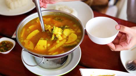 ladling soup into a bowl at a table