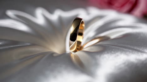 wedding ring on a satin pillow with rose