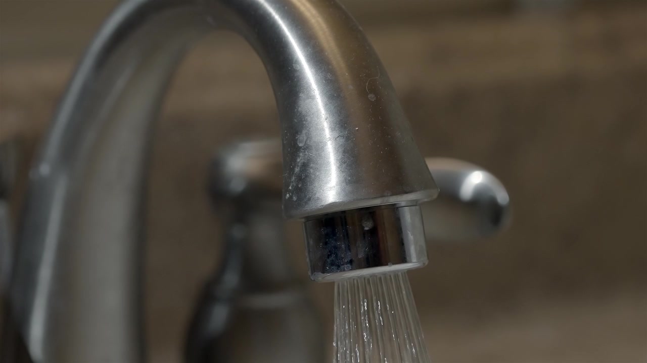 Acqua che scorre da un rubinetto del bagno cromato in primo piano