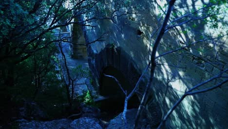 Arch-made-of-sandstone-in-a-forest,-small-underpass-dark-to-hide