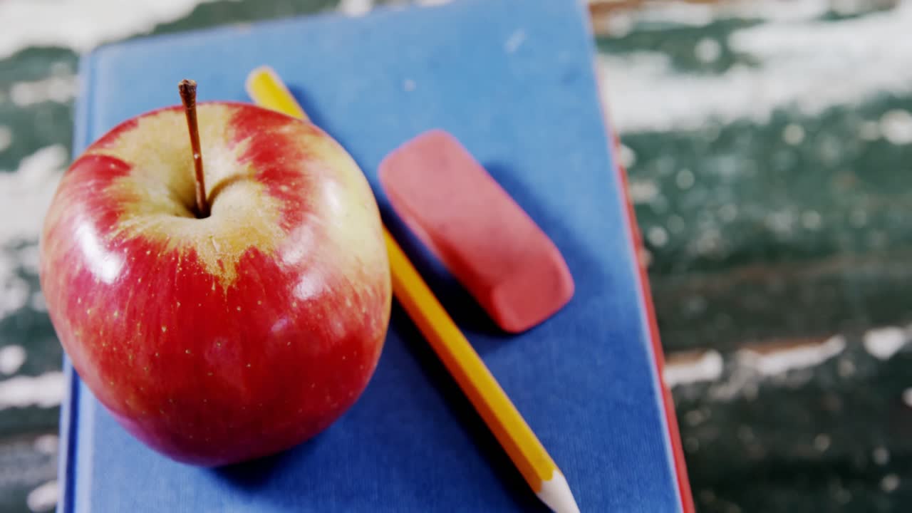 Apple, pencil and eraser on book stack