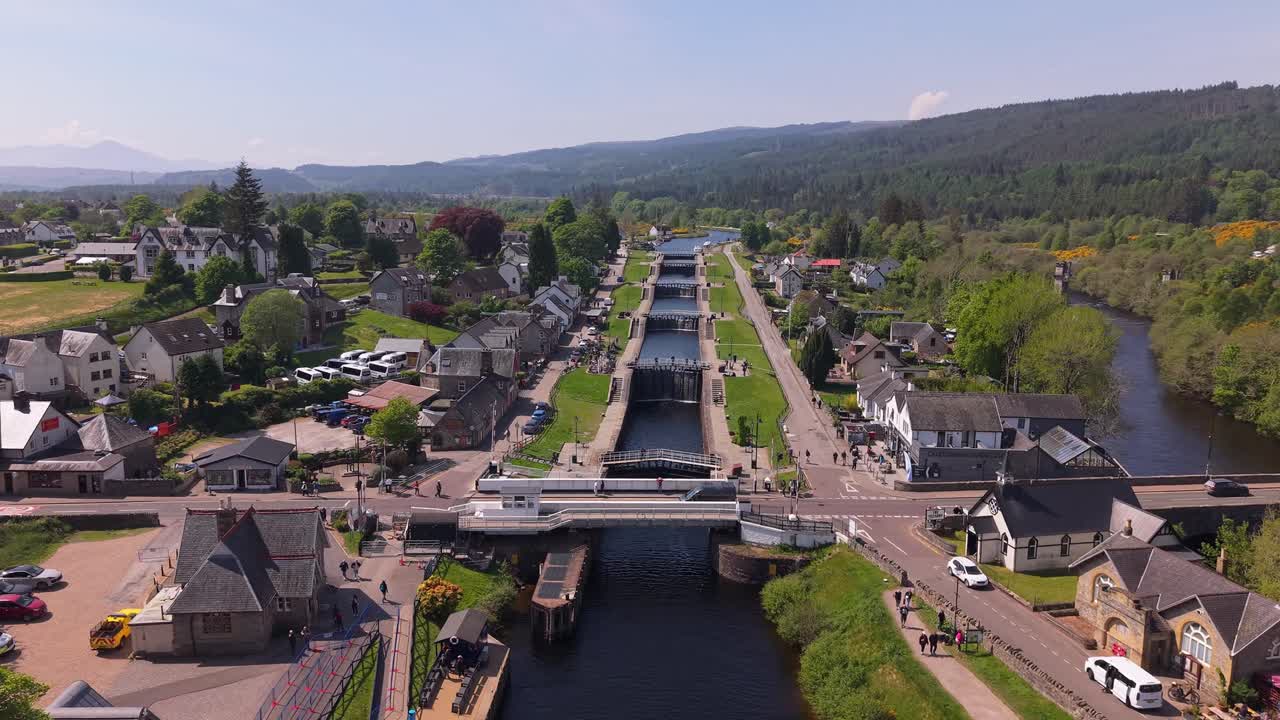 Aerial footage of Fort Augustus village in Scotland, showcasing the Caledonian Canal as it cuts through the heart of the town with scenic views of the Highlands