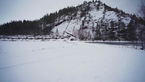 Distant-View-Of-An-SUV-Car-Driving-On-Snowy-Terrain-With-Mountain-Backdrop-In-Vestland-County,-Norway