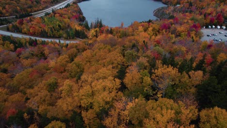 aerial of blue lake in the mountains surrounded by fall foliage