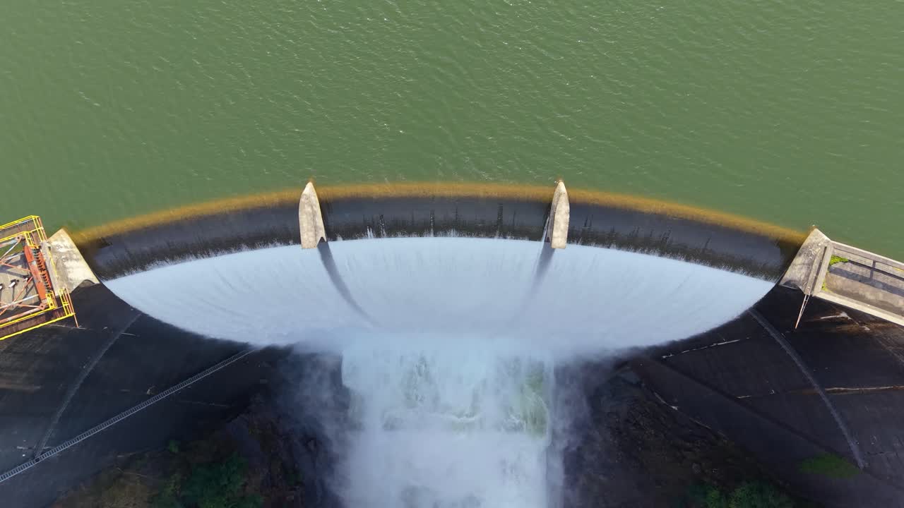 Vista superior de la presa de hormigón curva de Encoro do Eume liberando agua a través del aliviadero en Galicia, España. Revelación aérea con retroceso