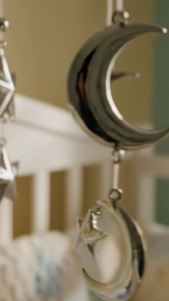 A Glimpse of Whimsical Silver Stars Hanging from a Baby Crib Mobile, Creating a Dreamy Atmosphere in a Softly Lit Nursery Setting