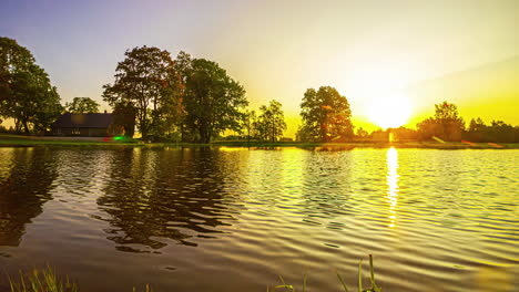 Sonnenaufgang-Im-Zeitraffer-Mit-Goldenem-Licht,-Das-Von-Der-Oberfläche-Eines-Teiches-Reflektiert-Wird