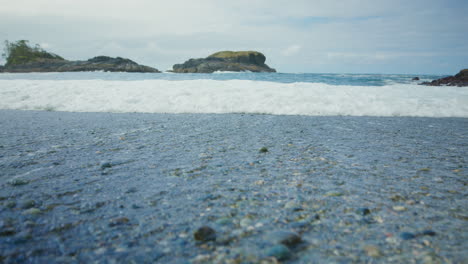 cerca de la vista del suelo de las olas del mar en la playa rocosa de guijarros slomo