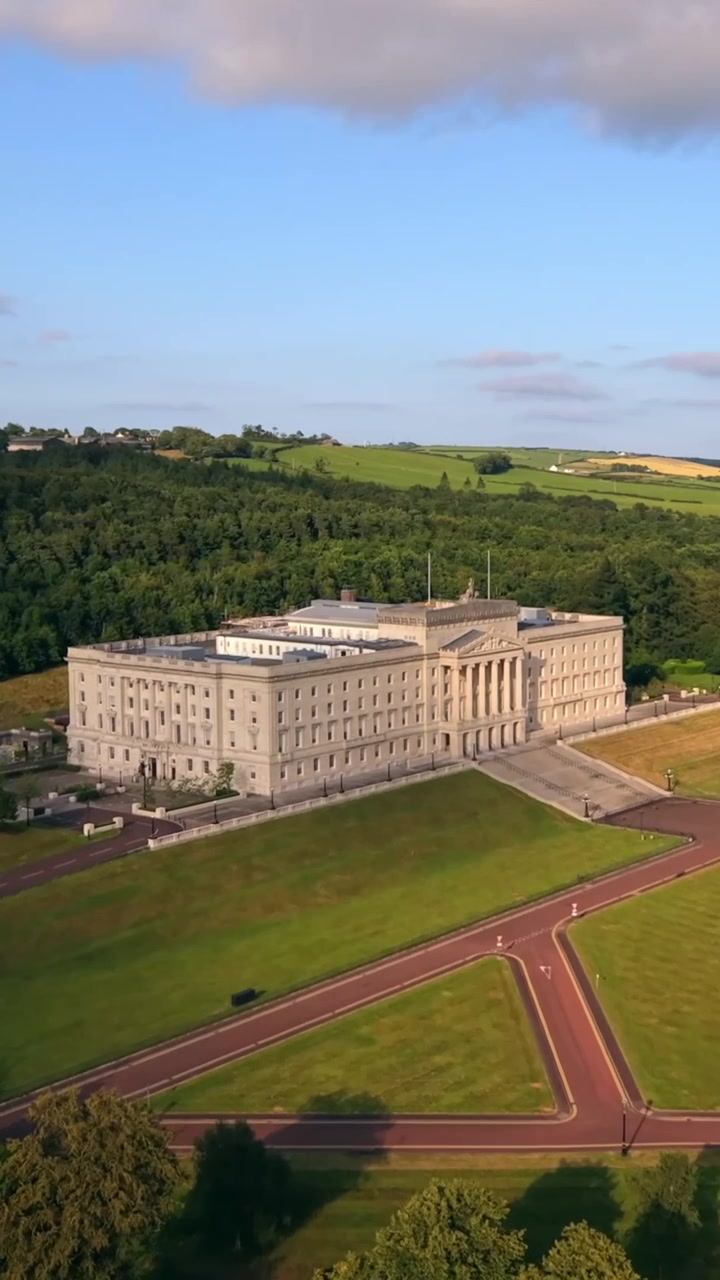 Přiblížený letecký videozáznam v 60 FPS s vertikálním poměrem pro sociální média, zachycující budovy parlamentu Stormont v Belfastu, Severním Irsku ve Spojeném království. Vyrobeno v barevném prostoru Rec709 pro vysílání.
