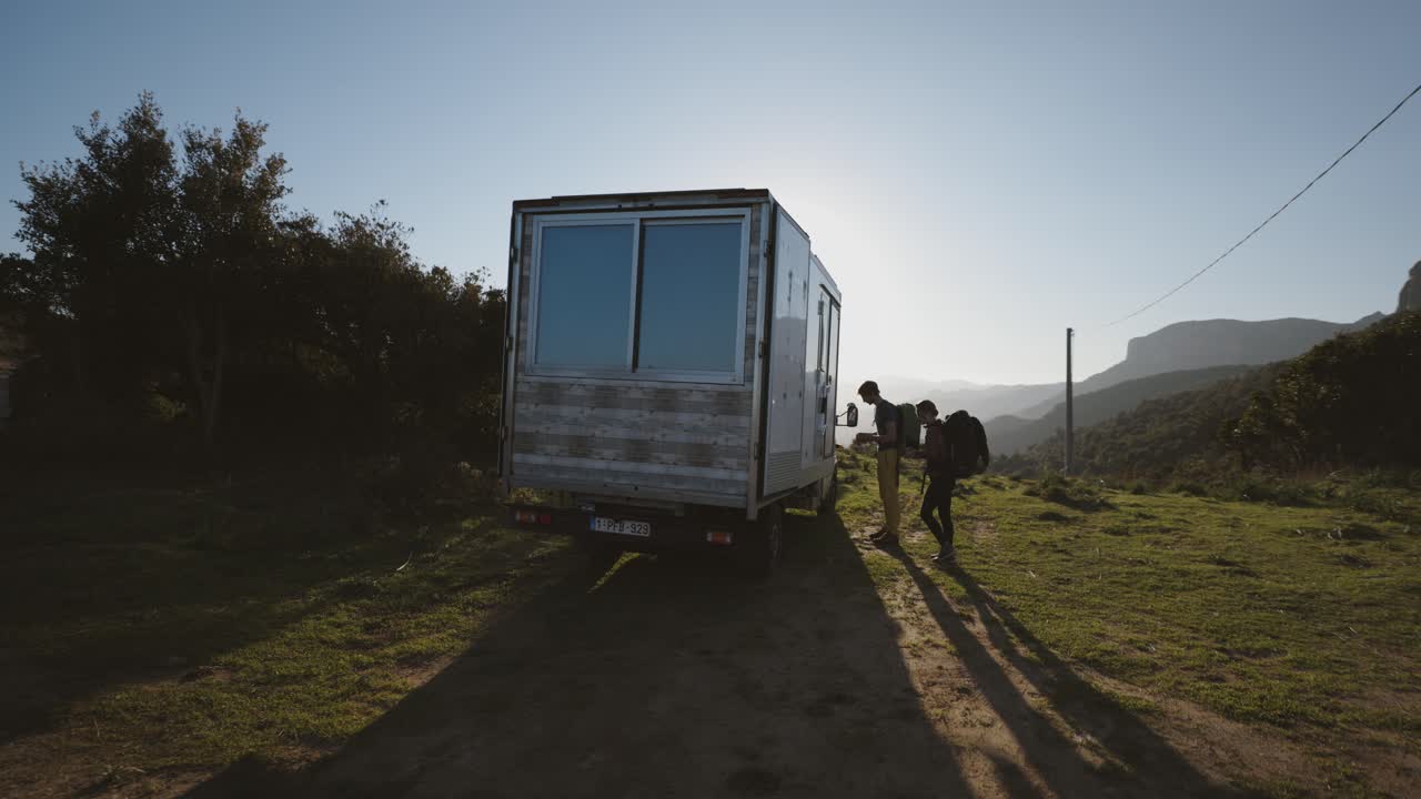 Couple Opening The Camper Van Parked On A Field On Sunny Day. medium shot