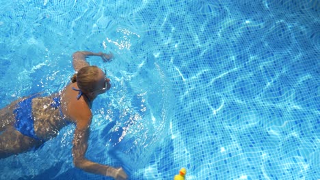 mujer nadando en la piscina en un día caluroso y soleado