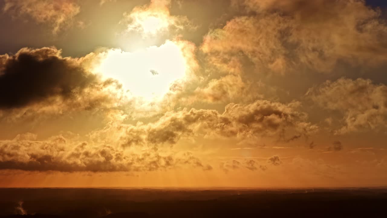 Timelapse of golden sunlight piercing layered clouds over a dark horizon during sunset
