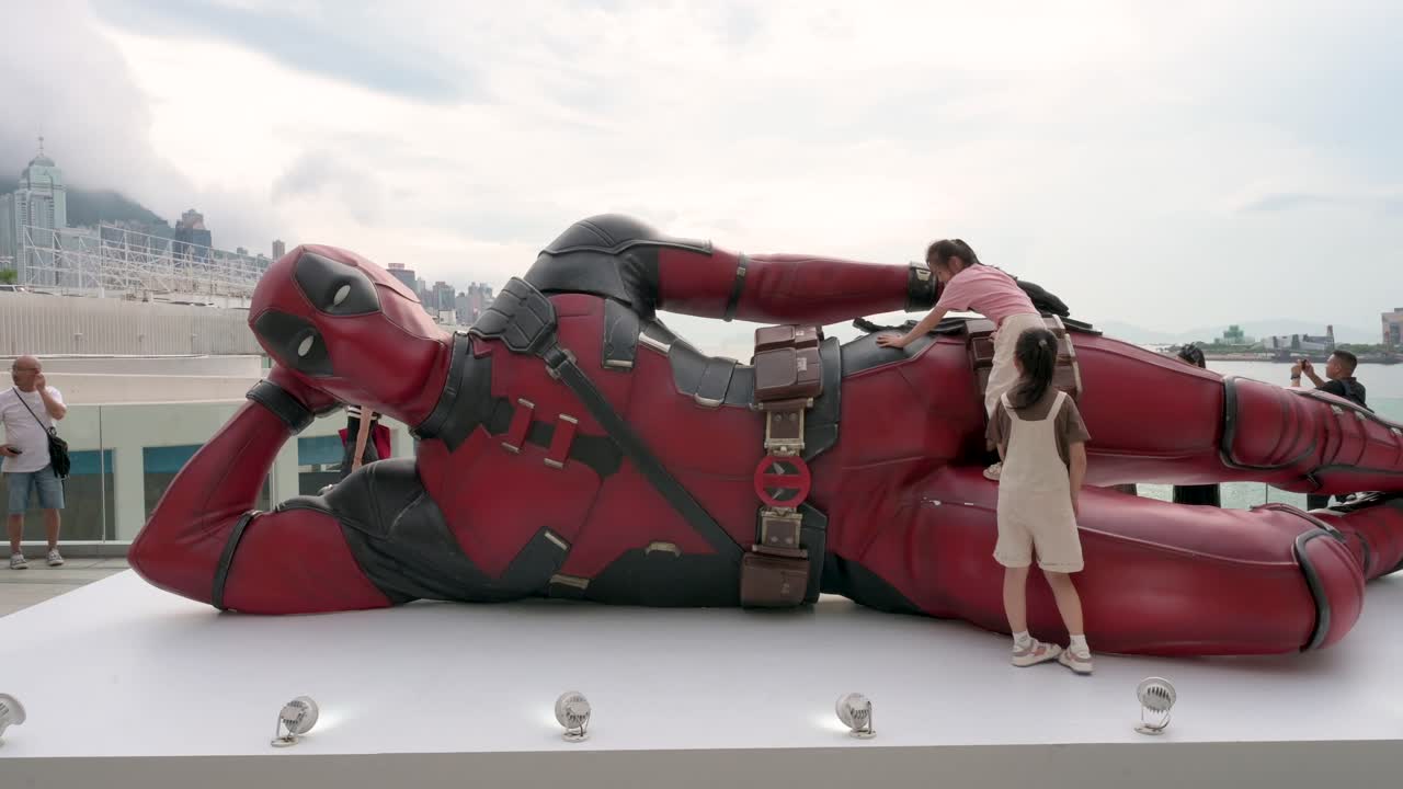 An 8-meter Deadpool installation in Hong Kong draws tourists and locals. Kids climb it as part of Disney’s "Deadpool and Wolverine" movie promotion.