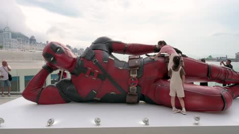 an 8-meter deadpool installation in hong kong draws tourists and locals. kids climb it as part of disney’s "deadpool and wolverine" movie promotion.