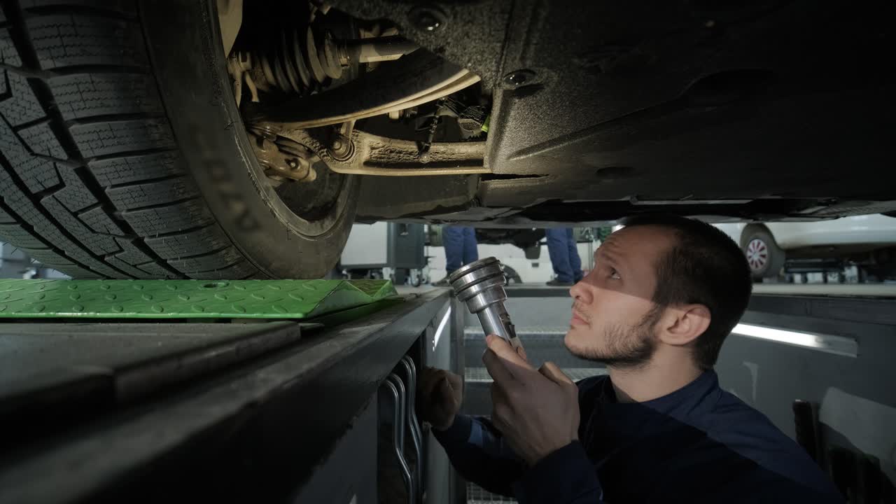 mecánico inspeccionando el tren de aterrizaje del automóvil en el pozo de servicio