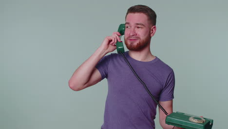 cheerful tourist man secretary talking on wired vintage telephone of 80s, says hey you call me back