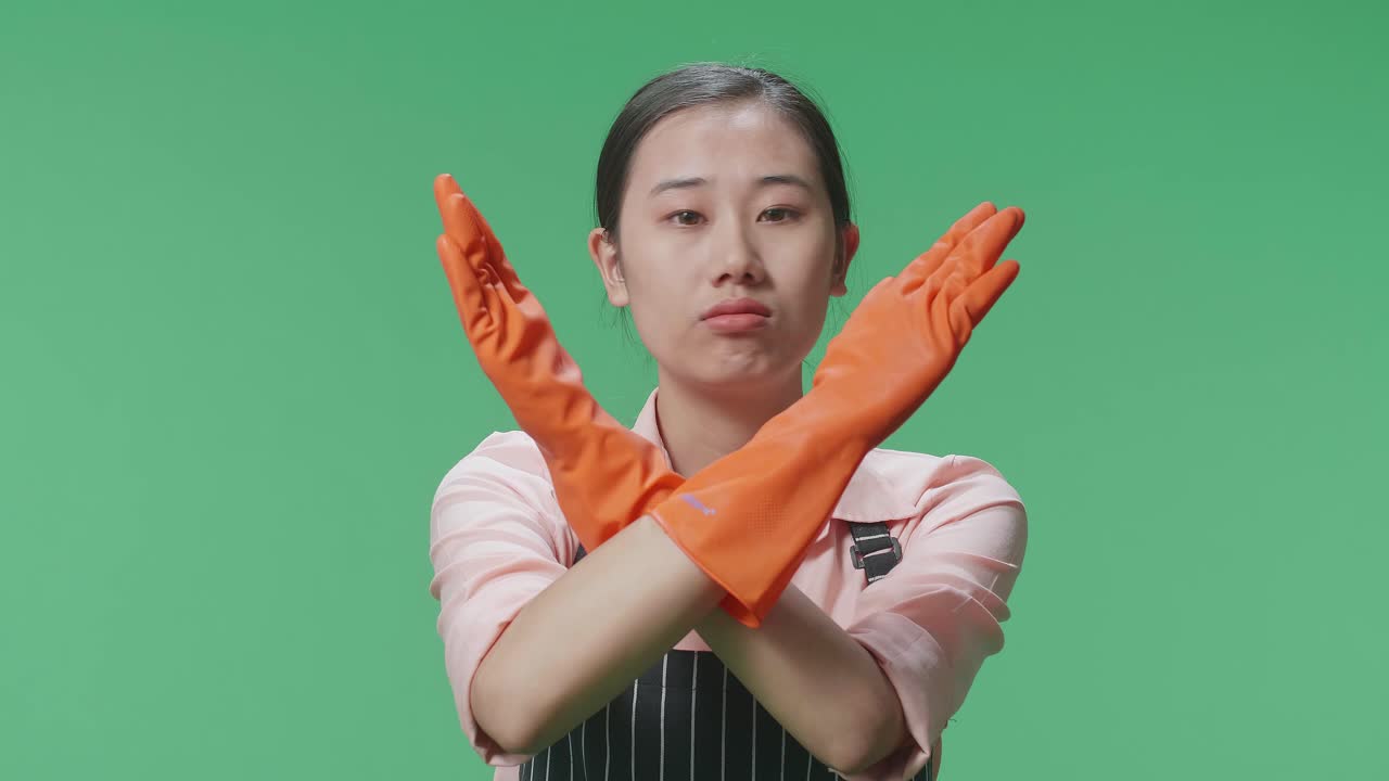 녹색 스크린 스튜디오에 서 있는 동안 금지 조치를 보여주는 전면으로 동의하지 않는 아시아 여성 집사