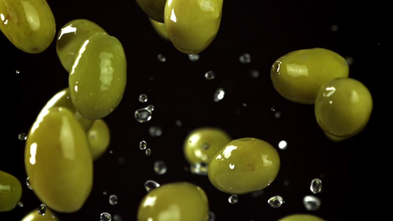 Olive verdi che cadono con gocce d'acqua al rallentatore
