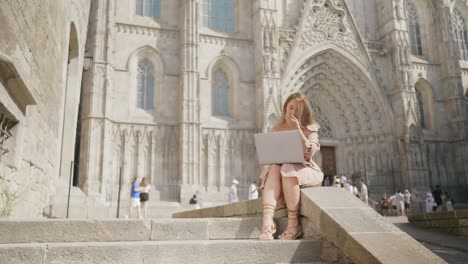 Lachende-Frau,-Die-Mit-Laptop-In-Der-Nähe-Der-Kathedrale-Arbeitet.-Lächelndes-Mädchen,-Das-Eine-Nachricht-Erhält