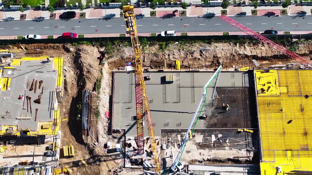 Flying above concrete foundations and tower crane at construction site
