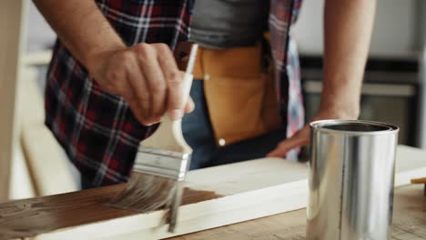 tilt down video of  man painting boards with a brush