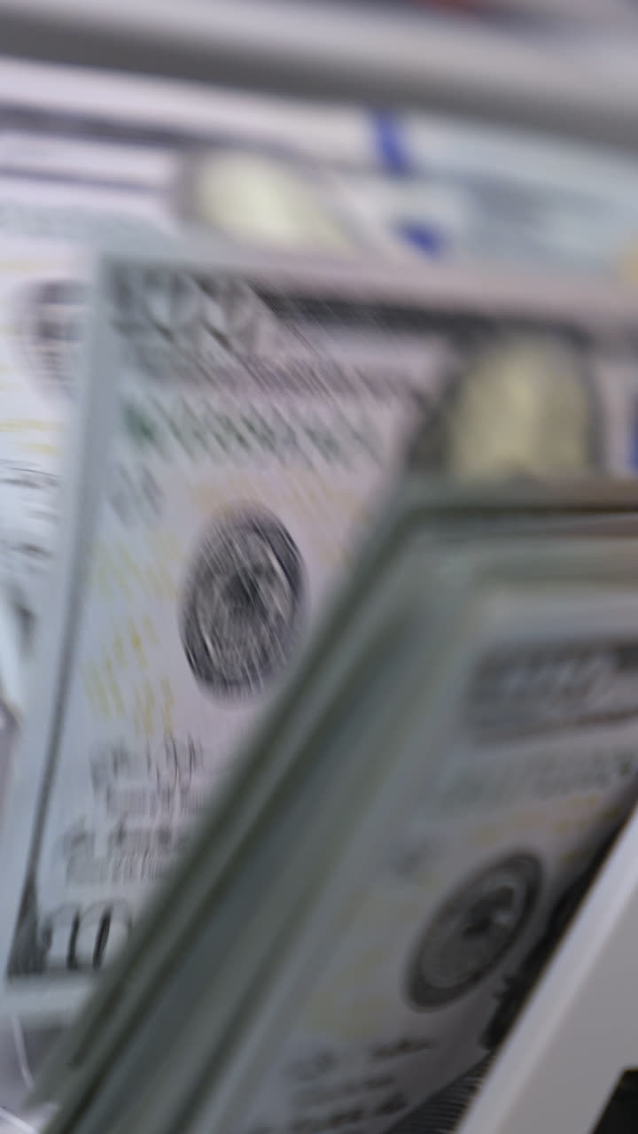 Money counting machine. Banknote counter are counting hundred dollar bills. Close-up Vertical video