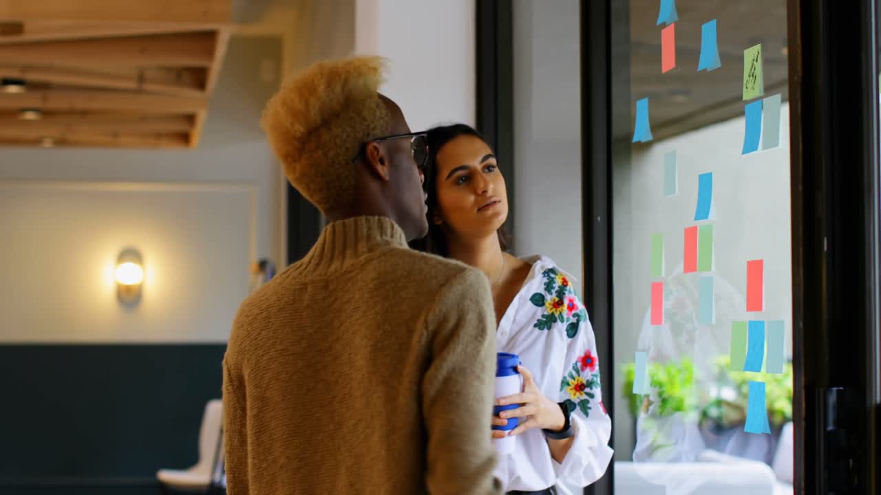 Young mixed race business colleagues discussing over sticky notes in modern office 4k