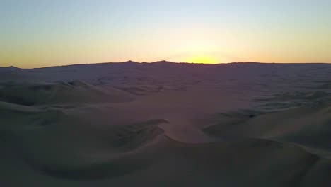 Vasto-Paisaje-Aéreo-De-Dunas-De-Arena-Con-Puesta-De-Sol-En-El-Horizonte