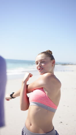 vertical video: stretching on beach, fit woman in sportswear preparing for workout