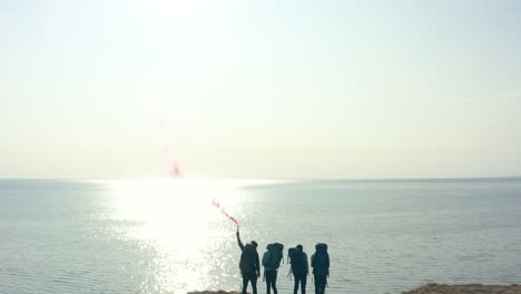 the tourists with fire stick standing on the top of sandy rock near the sea