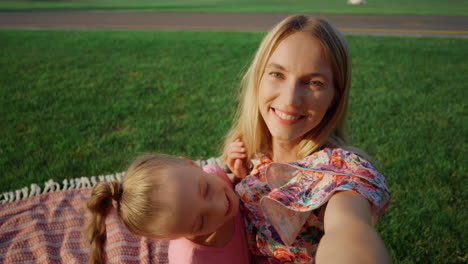 Happy-woman-hugging-girl-at-meadow.-Young-family-taking-selfie-outdoor.