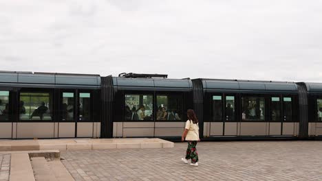 woman walking as tram departs in bordeaux