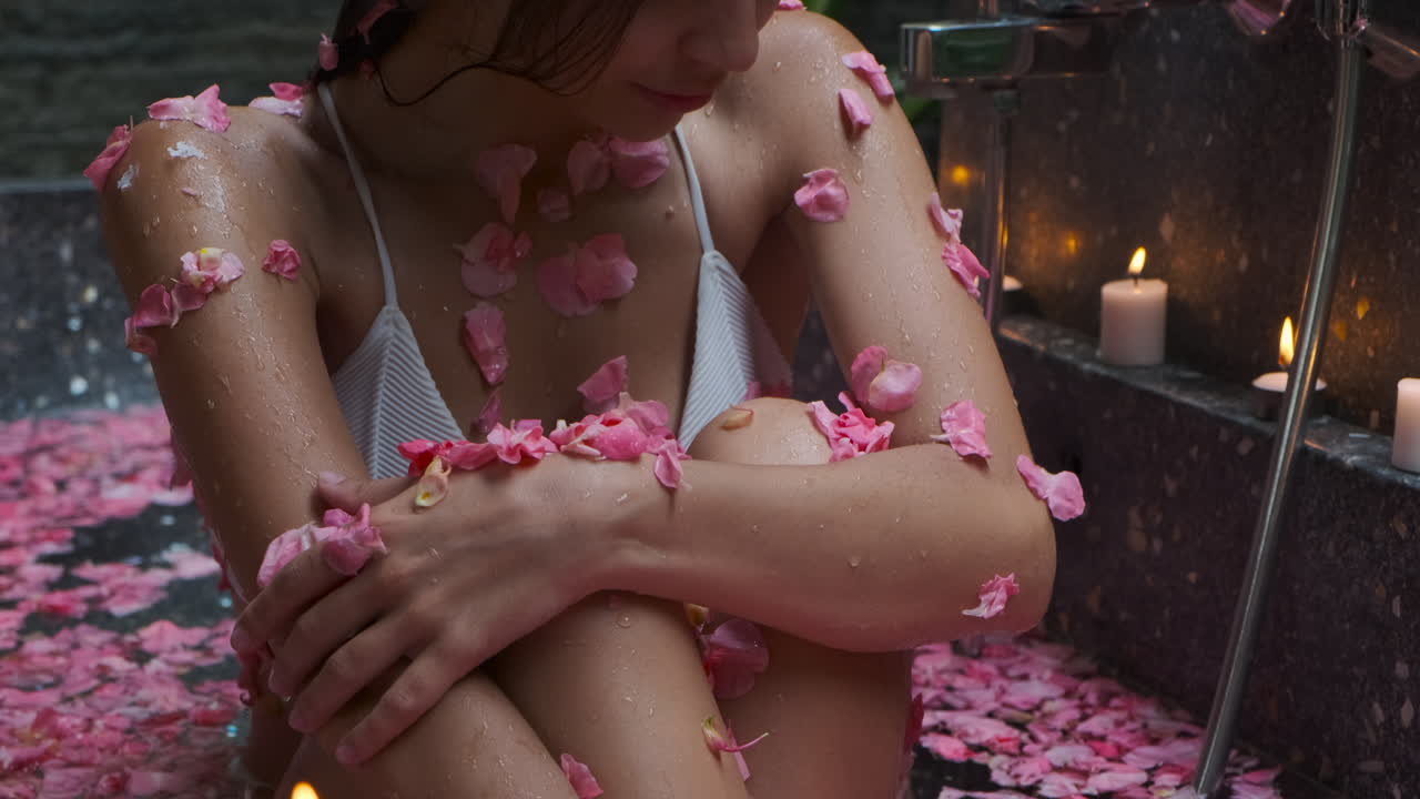 Donna che si gode un romantico bagno di petali di rosa