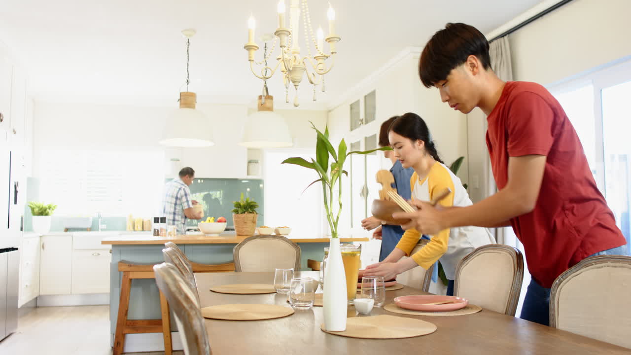 Setting dining table, family preparing for meal in modern kitchen together