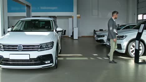 man looking at a white suv in a car showroom