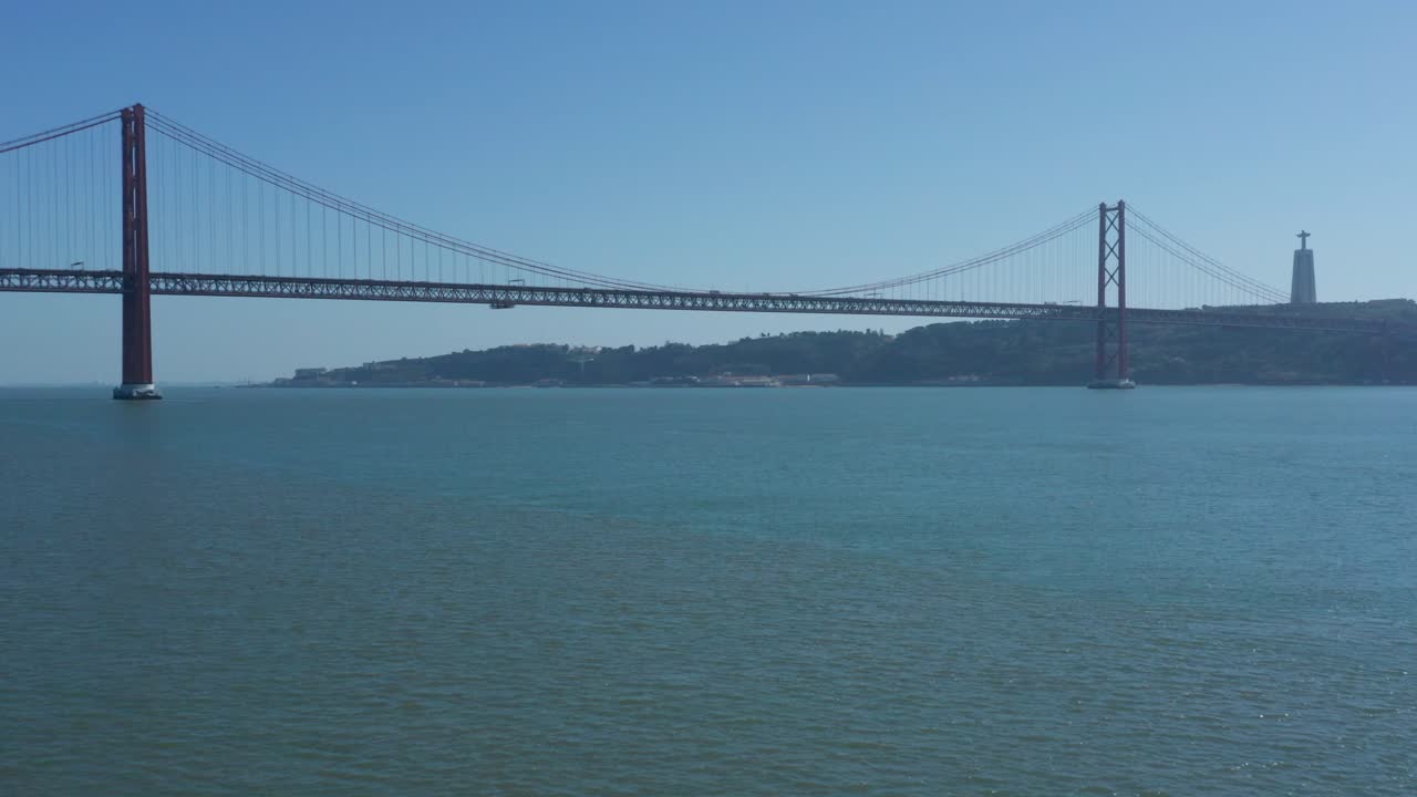 disparo de un dron sobre el río tajo con el puente 25 de abril - la estatua de cristo rey al fondo, portugal
