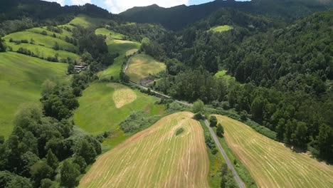 Lagoa-do-fogo-with-lush-green-fields-and-forested-hills,-aerial-view