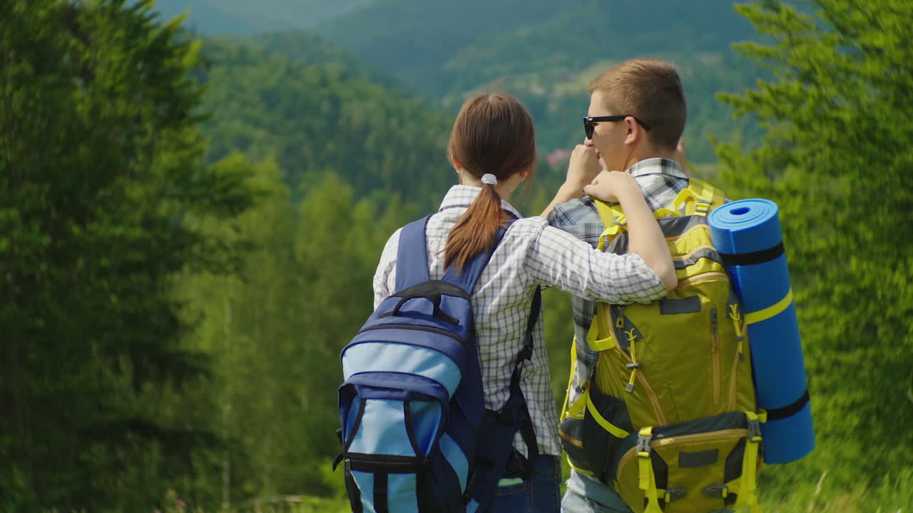 un par de viajeros con mochilas toman fotos de un hermoso paisaje montañoso vacaciones activas