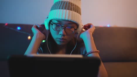 young asian woman listening to music on headphones and laptop