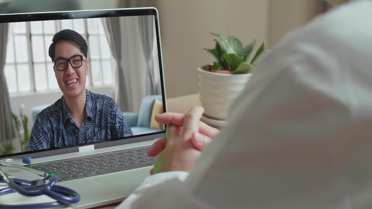 Primer plano de médico hablando con paciente por videollamada en portátil en el escritorio, video en 4K