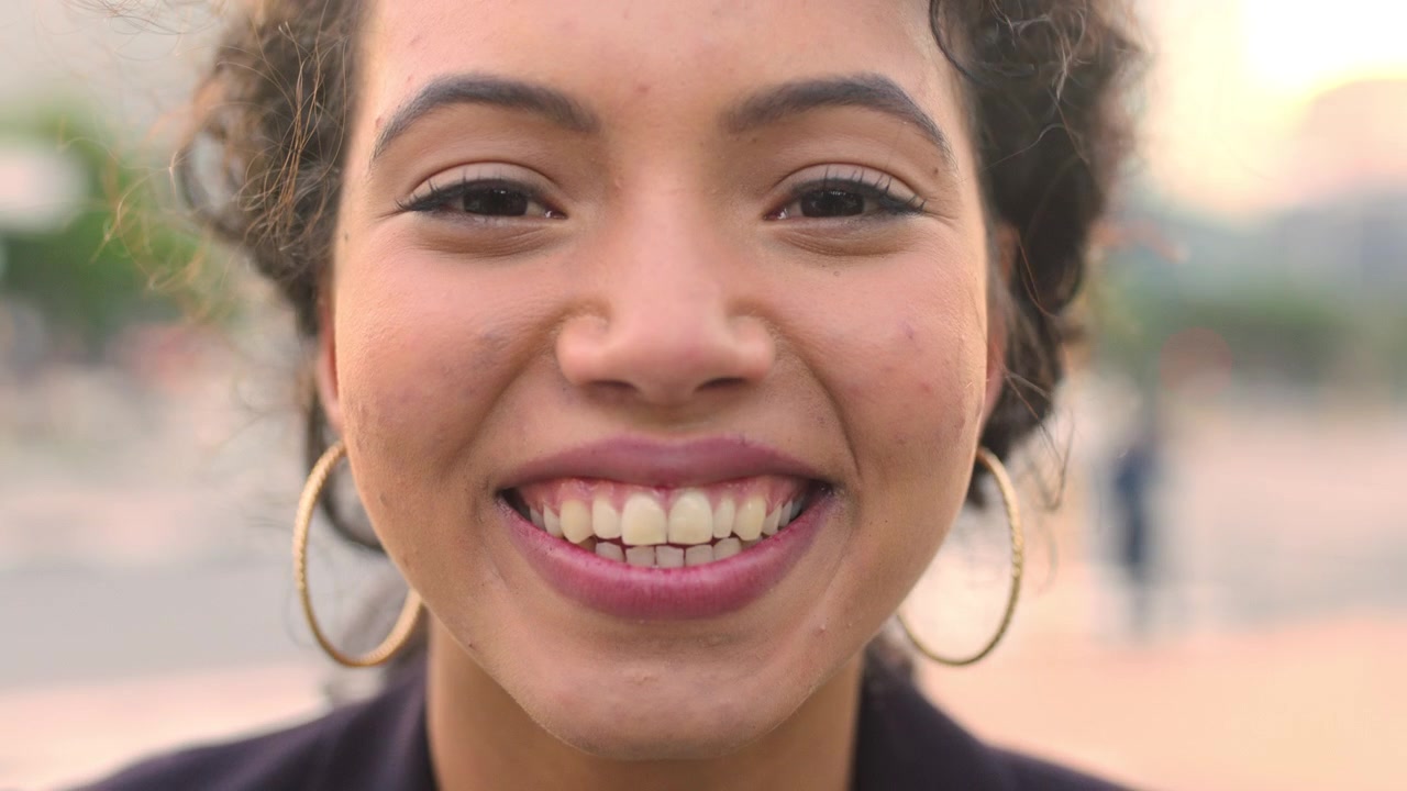 Close-up Portrait of a Smiling Young Woman Outdoors